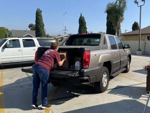 A volunteer from East L.A. Bilingual church loads a box from the food bank into the car.