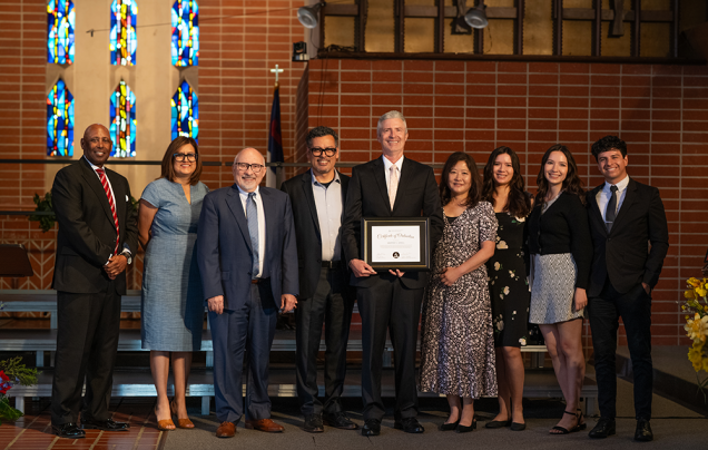 Sewell holds his ordination certificate, surrounded by colleagues and his family