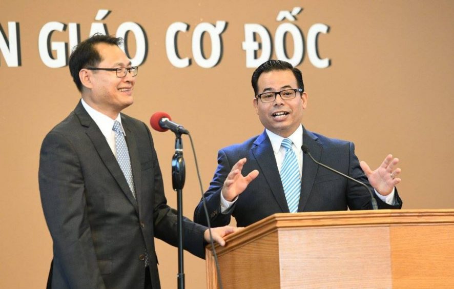 Pastor José Cortes (right) gives the main address, encouraging the students to remember that God loves them and they are to share that love with others. Pastor Vinh Nguyen (left) translates. Photo by Hien B. Tran