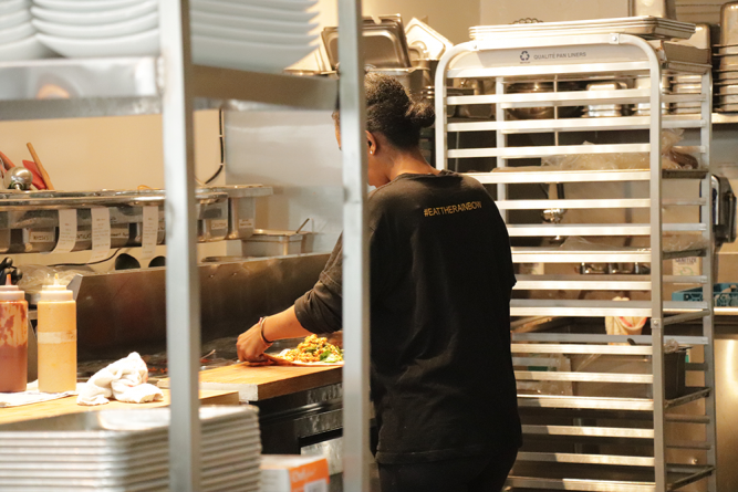 Alemayehu is seen preparing a meal in the open kitchen.