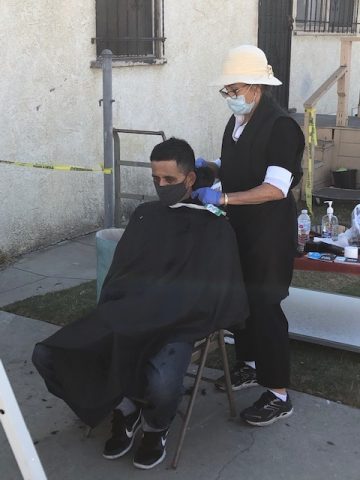 Maria (right), a volunteer from the community, gives free haircuts once a month.