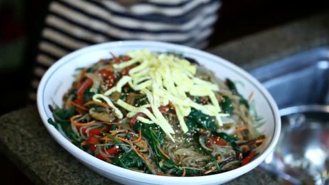 Kristi Lee tops her Korean japchae, a glass noodle stir-fry, with garnish.