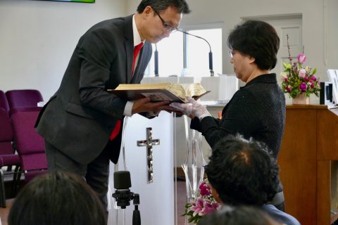 Kim (left) receives the handwritten Bible, which was written by members of Rosemead Korean church.