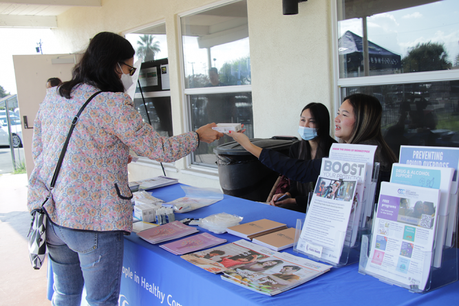 An attendee is given a Flowflex COVID-19 Antigen Home Test from the Los Angeles County of Public Health booth.
