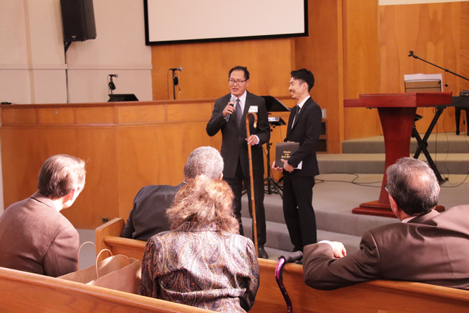 Nguyen (left) presents Shinasue (right) with a shepherd’s rod.