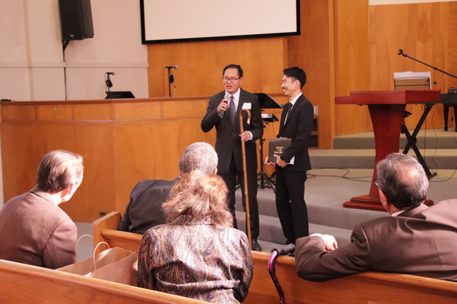 Nguyen (left)  presents Shinasue (right) with a shepherd’s rod.