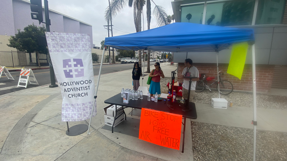 Volunteers stand by their bike stop
advertising free water and air. The Hollywood church building did
not have the required four feet of sidewalk space, so the tent was set up in front of the fire station on the opposite corner of the church.