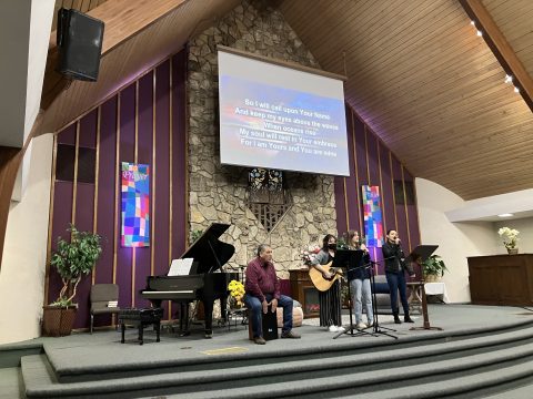 Phil (left) joins the youth praise team by playing the cajón during the week.