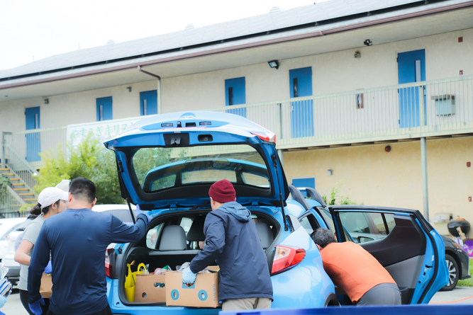 The food pantry is set up as a drive-thru. Like a NASCAR pit stop, volunteer teams assist the cars from both sides, bringing boxes of both fresh produce and shelf-stable foods.