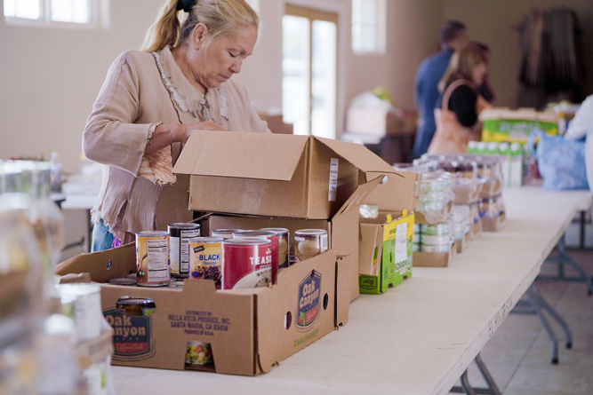 A volunteer replenishes the canned goods station in between distributions.