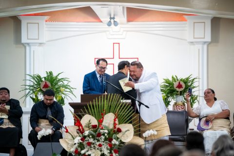 Previous Pastor Vunileva (left) and new Pastor Mo’unga (right) embrace after the passing of the torch (candle) ceremony.